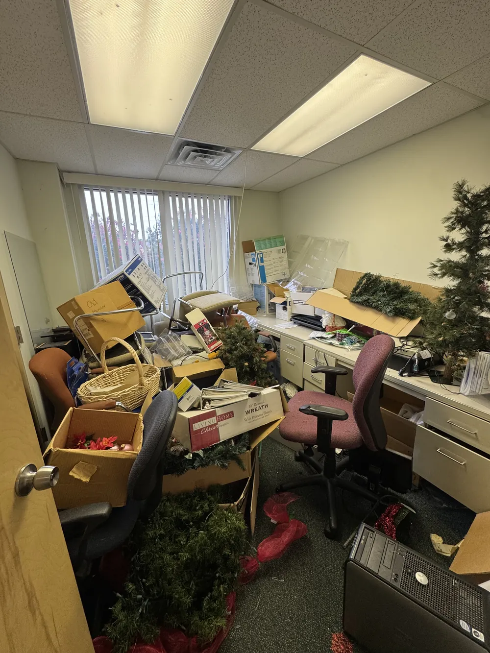 A small office packed with desks, chairs, boxes and Christmas decorations before a cleanout